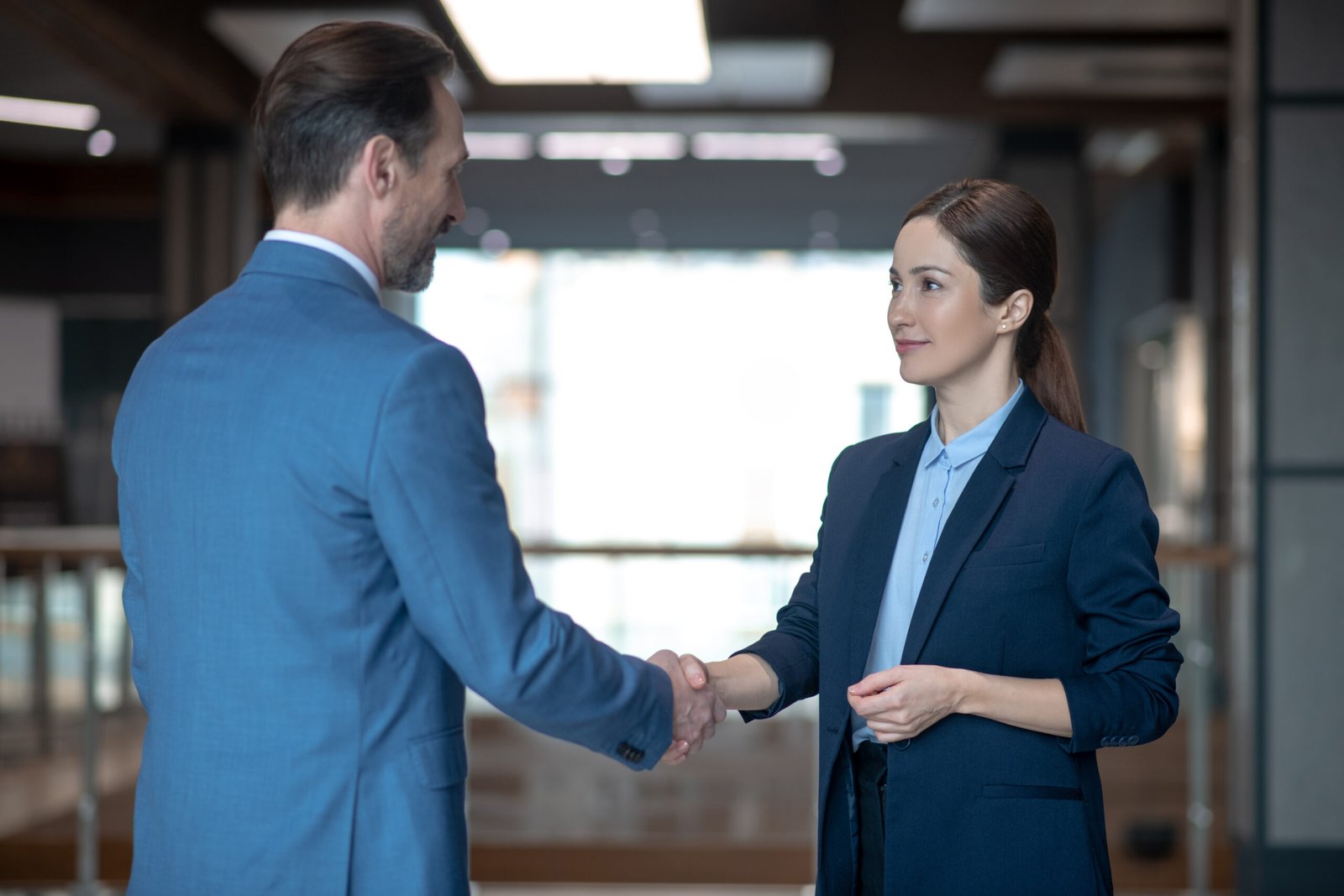 Lady shaking hand. Dark-haired business lady wearing dark jacket shaking hand of her investor while meeting